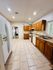 Spacious kitchen with sleek tile flooring, modern wooden cabinets, and ample natural light from large windows.