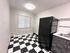 Charming kitchen with contemporary black and white checkerboard flooring, featuring a sleek black refrigerator and stylish white subway tile backsplash.