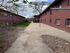 Charming red brick apartment building with lush green surroundings and a peaceful walkway, perfect for tranquil living.