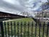Charming apartment exterior with lush green lawn, elegant black iron fencing, and inviting pathways under a picturesque sky.