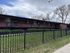 Charming brick apartment building with spacious green lawn and elegant wrought-iron fence, offering serene living in a picturesque neighborhood.
