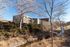 Charming apartment complex nestled among lush greenery with a serene creek and expansive blue sky view.
