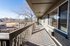 Charming apartment balcony with scenic view of a sunlit park and tree-lined horizon, perfect for relaxing outdoors.