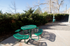 Charming outdoor patio with a vibrant green picnic table surrounded by lush greenery, perfect for leisurely afternoons.