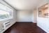 Bright and airy living area with large windows, sleek hardwood floors, and a cozy open kitchen design.