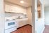 Inviting kitchen featuring white cabinets, modern appliances, and warm wood-style flooring.