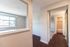 Inviting apartment hallway with elegant laminate flooring and bright natural light, featuring a glimpse into a cozy bathroom.