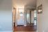 Modern apartment interior featuring bright bathroom with stylish vanity and mirror, mirrored closet doors, and elegant wood flooring, creating a welcoming and airy atmosphere.