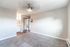 Bright and airy living space with modern ceiling fixture, beige carpet, and built-in storage, leading to a stylish bathroom with sleek fixtures.