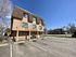 Inviting apartment building with ample parking, nestled in a serene neighborhood with clear blue skies.