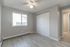 Bright and airy bedroom featuring large window, sleek closet doors, modern ceiling fan, and elegant wood-style flooring.