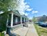Charming row of historic blue cottages with inviting front porches on a tree-lined street, under a vibrant blue sky.