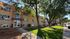 Charming apartment complex with a brick facade, surrounded by lush trees and well-maintained greenery, offering a peaceful urban living environment.