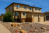 Charming two-story home with dual garages, surrounded by a low-maintenance desert landscape under a clear blue sky.