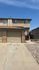 Charming two-story apartment with attached garage and inviting pathway, surrounded by a tidy rock landscape.