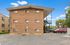 Charming brick apartment building with outdoor staircase, ample parking, and clear blue skies.