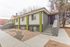 Charming modern apartment building with vibrant accents and inviting entrance, surrounded by a tidy xeriscape garden.