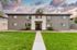 Charming two-story apartment building with spacious windows, set against a vibrant sunset sky, surrounded by well-manicured greenery.