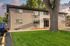 Charming apartment building exterior with lush green lawn and mature tree, perfect for peaceful living.