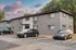 Charming two-story apartment building with ample parking and a serene ambiance, highlighted by a picturesque sunset sky.