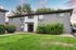 Charming two-story apartment building with modern gray exterior, surrounded by lush greenery and a well-manicured lawn.