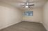 Inviting room with sleek wood flooring, modern ceiling fan, and large window providing natural light.