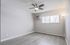 Bright, modern room with sleek laminate flooring, large window, and elegant ceiling fan.