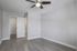 Bright and airy empty room with sleek gray flooring, a modern ceiling fan, and a white door opening to a closet space.