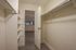 Spacious walk-in closet with ample shelving and hanging space, leading into a bright and airy room with wood flooring.