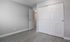 Modern, sunlit empty room with light gray walls, elegant hardwood flooring, and a convenient sliding closet door.