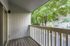 Charming apartment balcony with wooden decking and tranquil views of lush green trees, perfect for serene outdoor relaxation.
