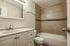 Elegant bathroom featuring modern fixtures, pristine cabinetry, and a sleek bathtub with tiled walls.
