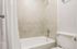 Bright, modern bathroom featuring elegant tiled walls and a pristine white bathtub with chrome fixtures.