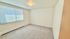 Bright and spacious bedroom with large window, plush carpeting, and natural light creating a warm and inviting atmosphere.