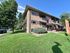 Charming two-story brick apartment building with lush green lawns, large windows, and a welcoming entrance. Now leasing sign signifies immediate availability in this appealing neighborhood.