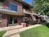 Charming brick apartment building with large windows, lush green lawn, and inviting entranceway, perfect for modern living.