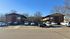 Charming brick apartment complex with ample parking, surrounded by trees for a serene living environment.