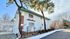 Charming white apartment building with unique exterior, surrounded by lush greenery and a spacious driveway.