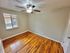 Bright room with polished wood floors, neutral gray walls, and a large window allowing natural light.