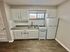Charming compact kitchen with modern white cabinetry, sleek countertops, and a cozy stove, perfect for city living.
