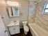 Charming bathroom with elegant marble tiles and a sleek vanity mirror, offering modern comfort and style.