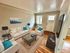 Inviting living room with elegant white sofas adorned with vibrant teal cushions, complemented by sleek black lamps and a sophisticated glass coffee table on a classic rug. Sunlit ambiance highlights the polished wooden floors and contemporary decor.