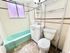 Bright and charming bathroom with a vintage green bathtub, modern sink, and stylish shelving unit.