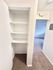 Bright and airy hallway featuring built-in shelving, modern carpeting, and a glimpse of an inviting room, ideal for streamlined storage and spacious living.