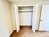 Bright and inviting closet space with white double doors and plush carpet flooring, perfect for organization in a cozy apartment.