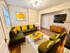 Chic living room featuring a contemporary green sofa with vibrant yellow accents, a modern coffee table, and a large wall-mounted TV, illuminated by stylish lighting.