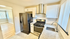 Modern kitchen with sleek white cabinets, stainless steel appliances, and elegant tile flooring leading into a bright living area.