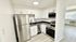 Modern kitchen with sleek stainless steel appliances, elegant white cabinetry, and a stylish black marble countertop, blending seamlessly into an open, airy layout.