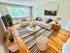 Chic and inviting living room with elegant decor, featuring a plush sofa, stylish striped rug, and abundant natural light from large windows overlooking greenery.