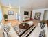 Charming living room with elegant decor featuring cozy sofas, a stylish striped rug, and lush greenery. Bright room with modern flat-screen TV and sleek wooden flooring.
